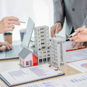 People discuss business and commercial law with model buildings and documents.