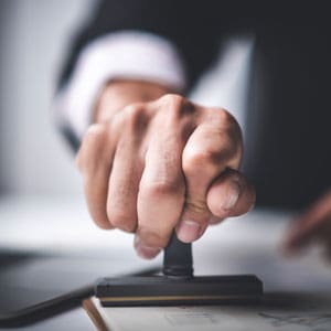 A hand stamping a document, symbolizing business licensing