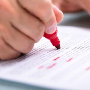 Reviewing contract details with a red pen to avoid common mistakes for new business owners.